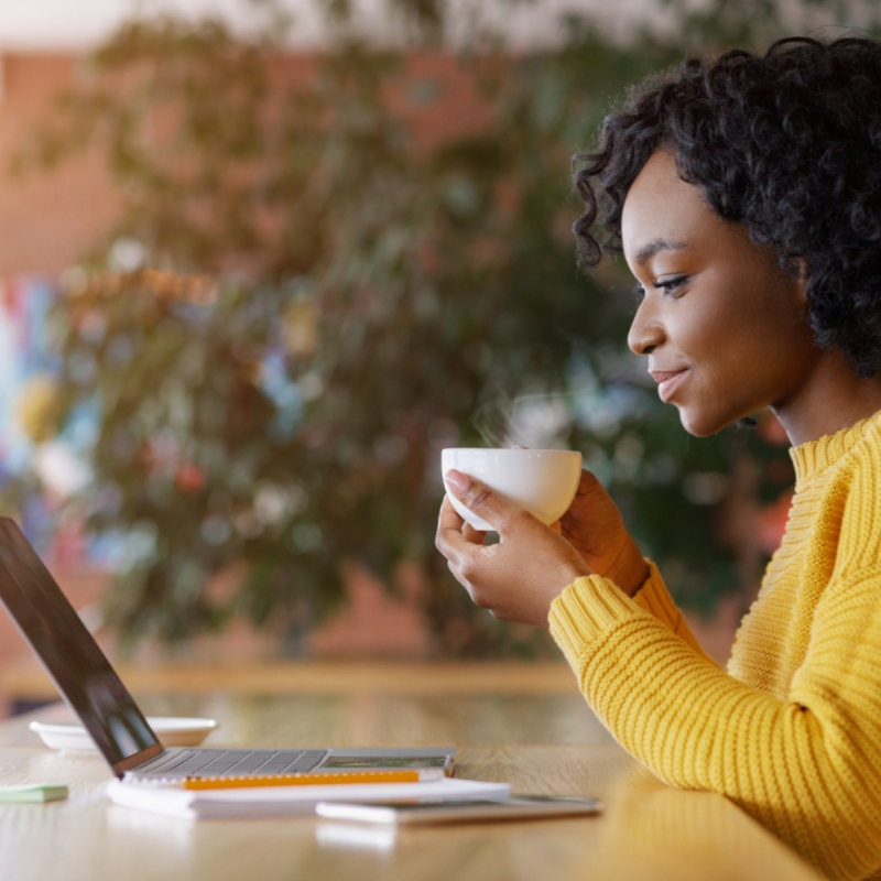 A woman enjoys a cup of coffee while visiting her website